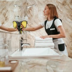 In the bathroom. Young chambermaid is in hotel room.